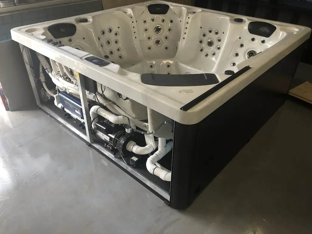 Hot tub repair with the cabinet open showing pumps and plumbing