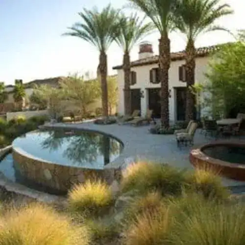 Half above ground hot tub placement beside a pool with landscaping