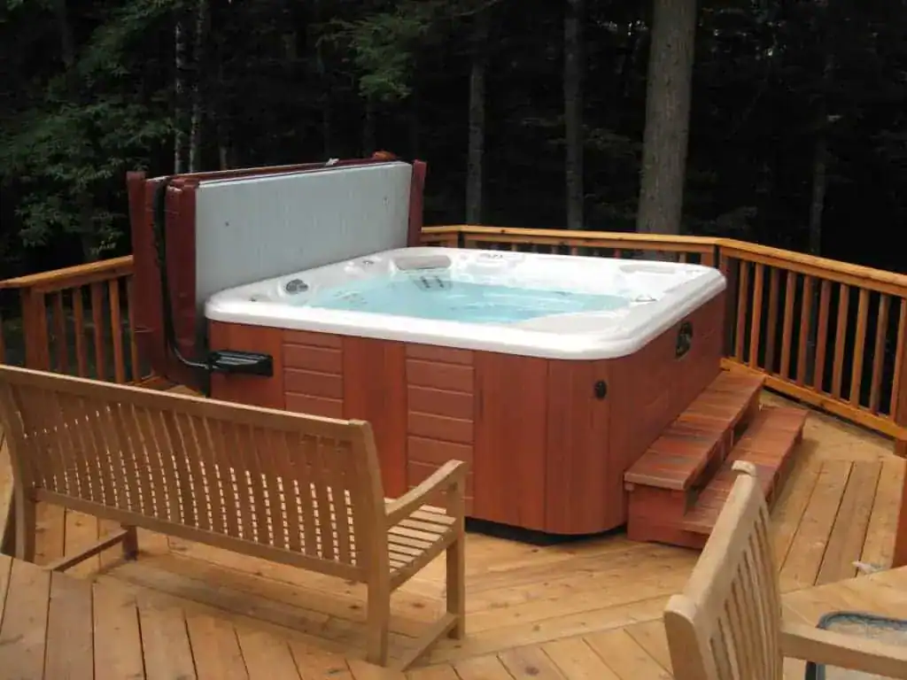 Hot tub installed on a reinforced wood deck base with steps and a cover lifter