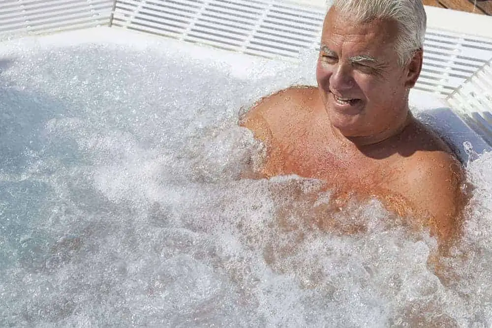 Man using hot tub hydrotherapy to ease back and muscle pain