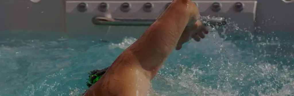 Swimmer stroking against the current in a swim spa, a compact alternative to a swimming pool